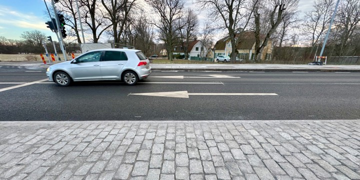 Grå bil åker på en väg in i en korsning  