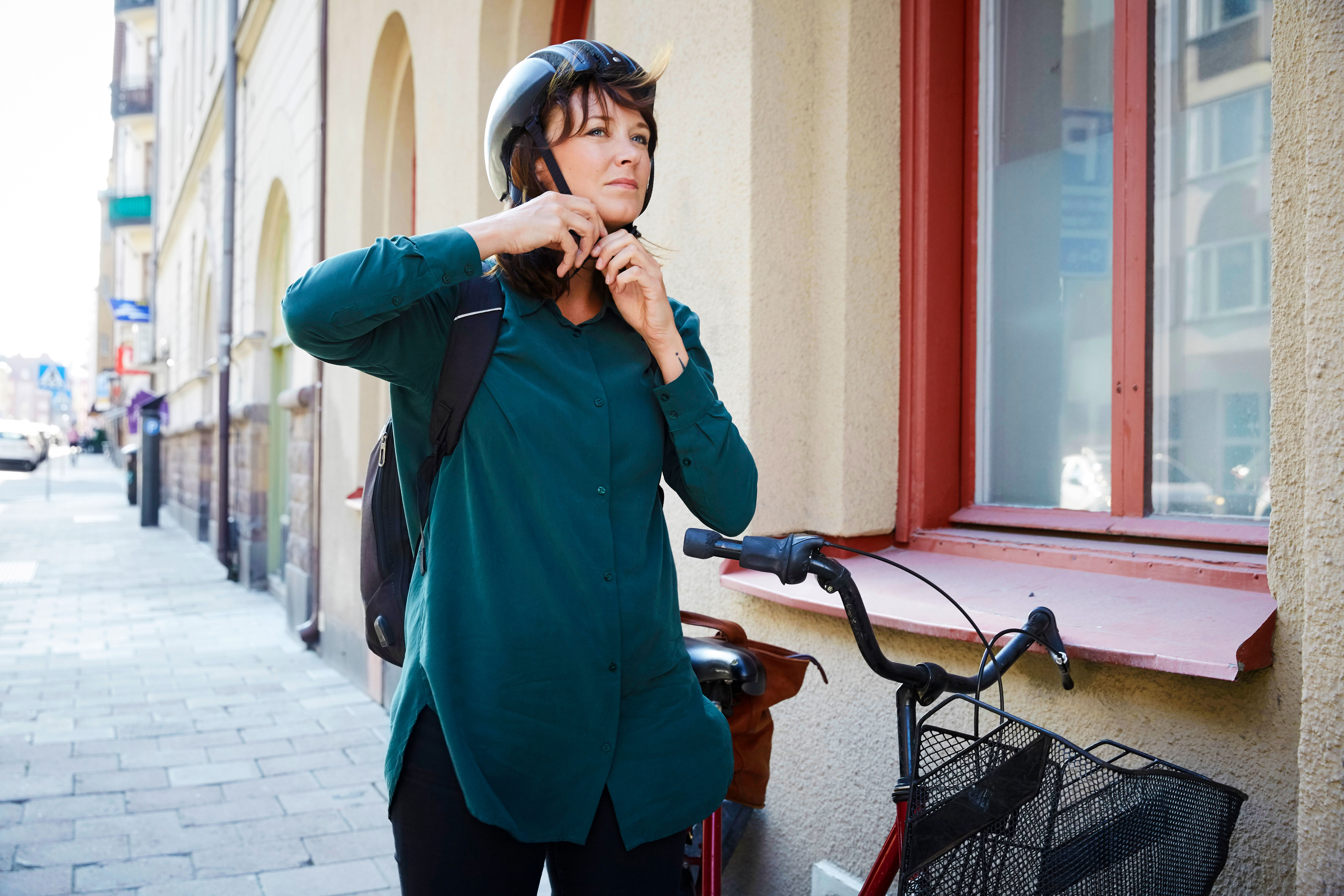 Kvinna som sätter på sig en cykelhjälm