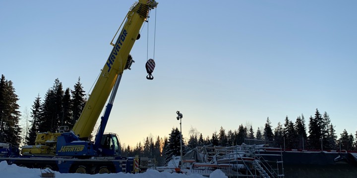 Lyftkran i vinterlandskap, med motljus