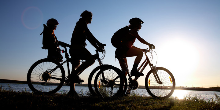En familj på cykeltur i solnedgången