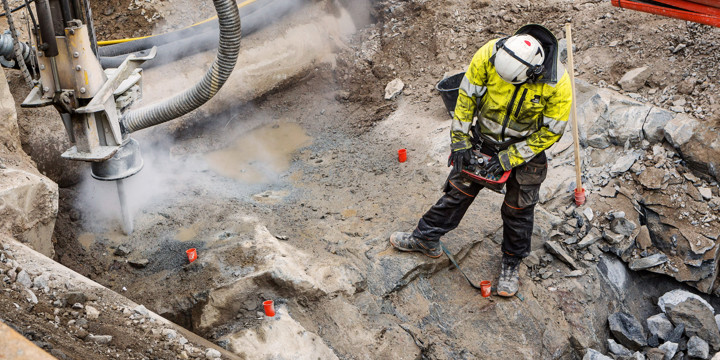 En sprängarbetare styr en borr som borrar hål i berget.