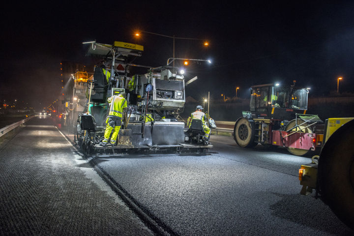 vägarbetare som lägger asfalt under kvälls-/nattetid