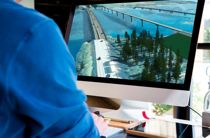 Person sitter framför dator med 3d-rendering över en väg- och en järnvägsbro 