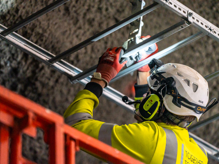 Varselklädd arbetare monterar kabelränna i tunneltak