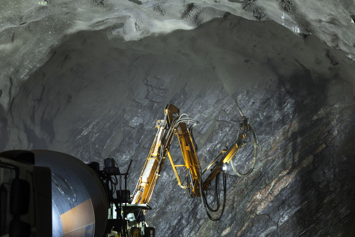 Tunnel i berg förstärks med betong med hjälp av maskin.