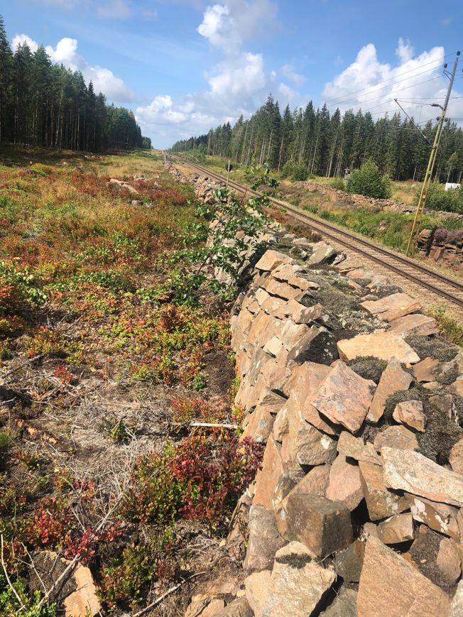 En stenmur som går längs med järnvägen i Väse.
