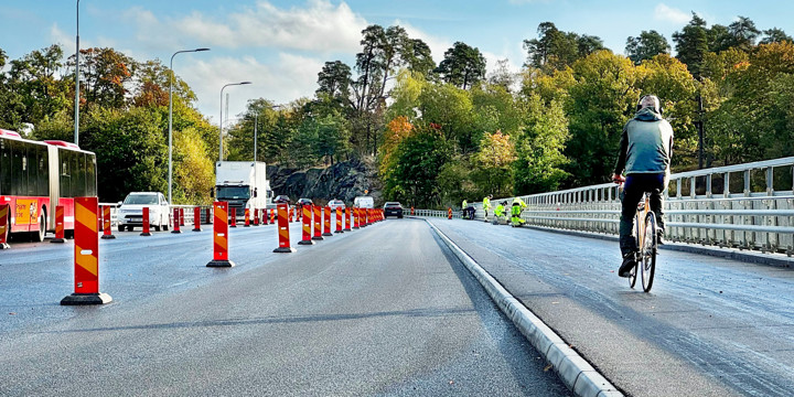 Cyklist cyklar på en nyasfalterad väg medan vägbygge pågår intill 