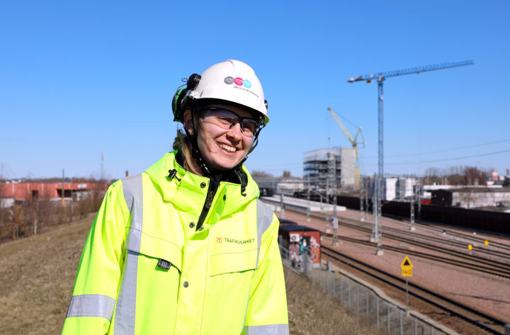 Gulklädd person står intill järnvägsspår.
