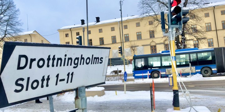 Väg med blå buss och en skylt som pekar mot Drottningholms slott