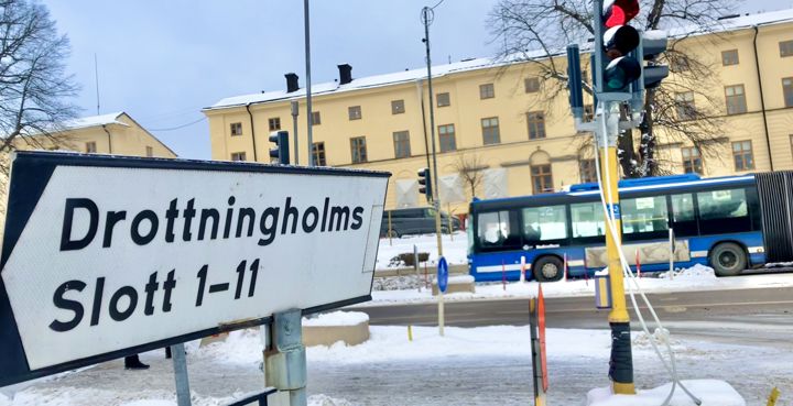 Väg med blå buss och en skylt som pekar mot Drottningholms slott 