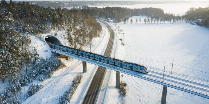 Ett tåg åker över en bro i ett vintrigt landskap.