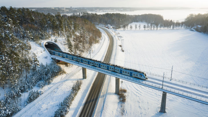 Ett tåg åker över en bro i ett vintrigt landskap.