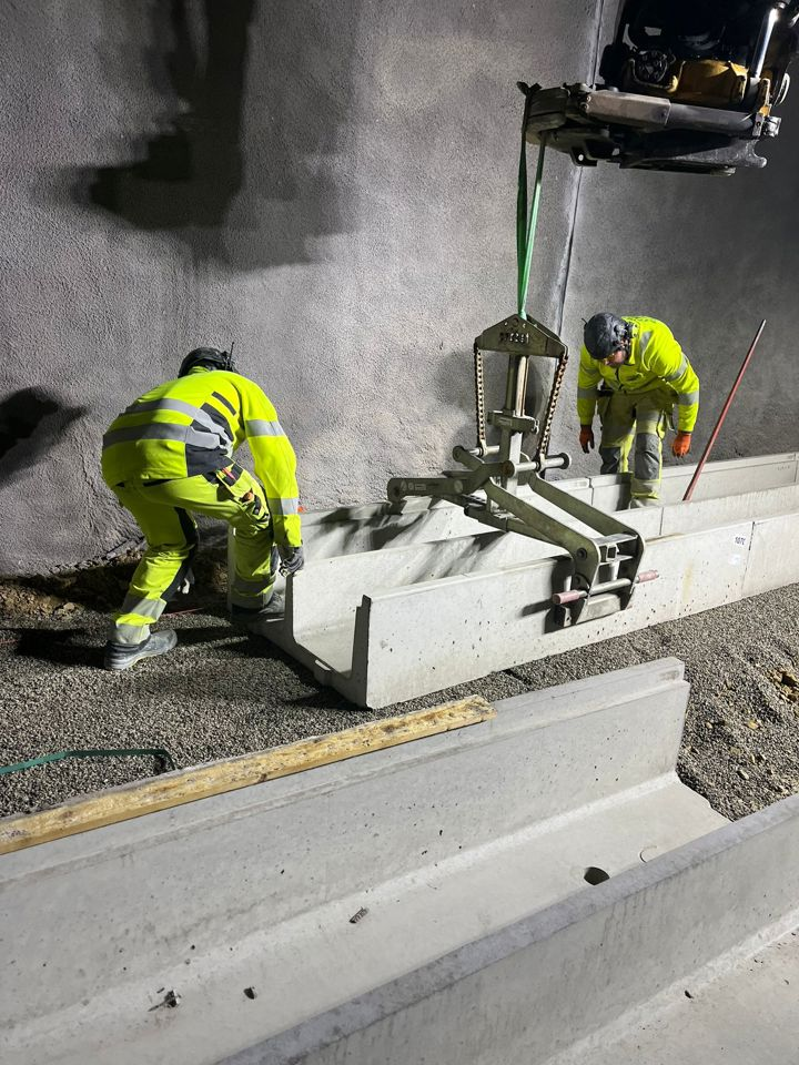 Två arbetsklädda personer står intill ett betongrör-