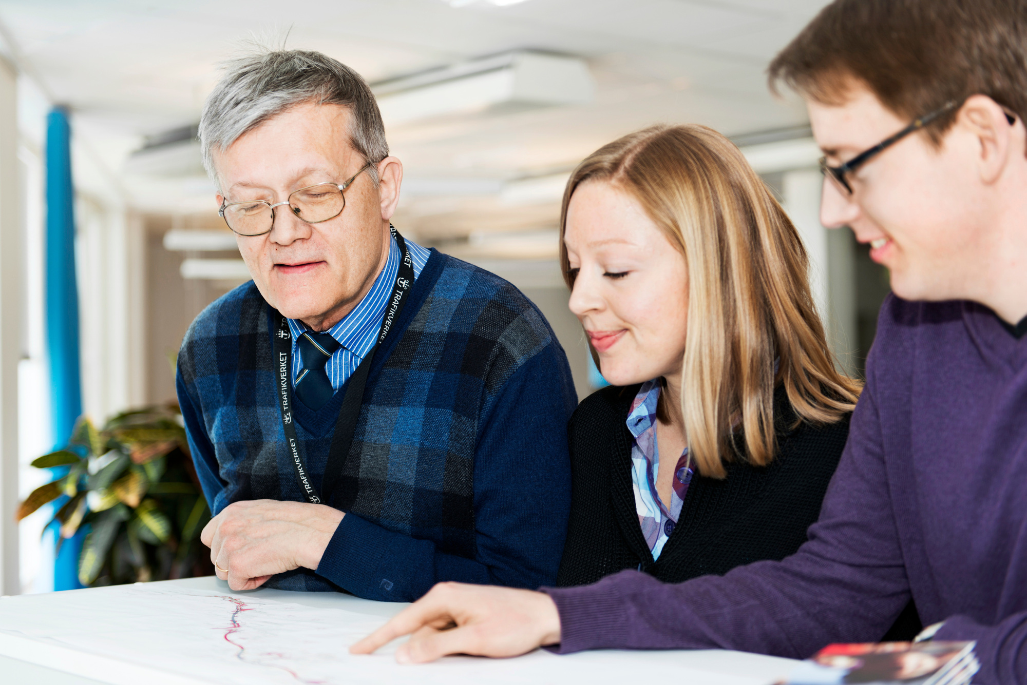 Tre personer tittar på en ritning.