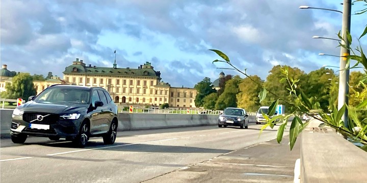 Bilar åker över en bro med ett slott i bakgrunden.