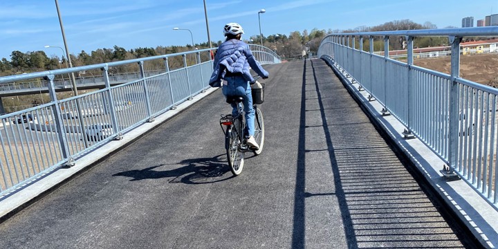 Bilden visar en kvinna som cyklar på gång och cykelbro.