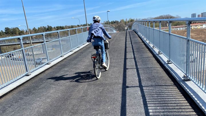 Bilden visar en kvinna som cyklar på gång och cykelbro.
