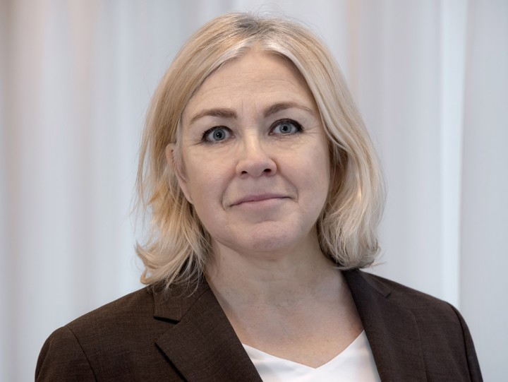 En svartvit bild på en leende kvinna med axellångt, ljust hår.