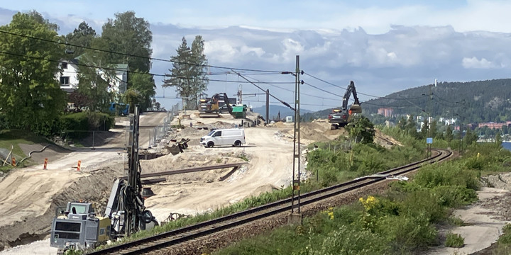 Befintlig järnväg sträcker sig i en kurva in mot centrala Sundsvall. På ena sidan järnvägen är Sönderborgsgatan en tillfällig grusväg och i arbetsområdet är ett flertal maskiner. Utkikstornet skymtar på Norra berget i bakgrunden samt några flerfamiljshus.