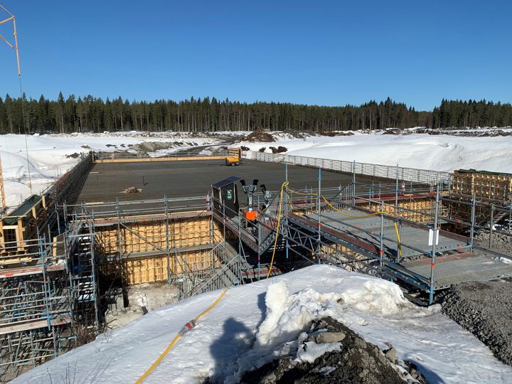 En byggarbetsplats för en bro syns mot en vintrig bakgrund med blå himmel