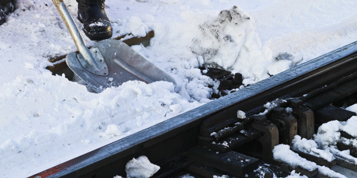 Människa skottar järnvägsräls från snö.