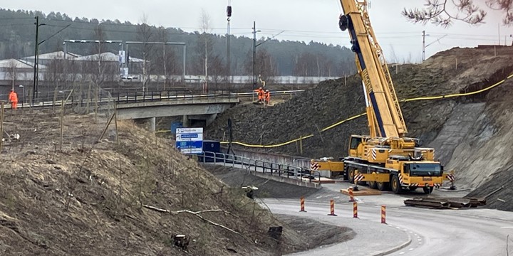 Spontarbeten vid Björneborgsgatan. Vid järnvägsbron står stor och en hög byggkran som upptar gång- och cykelvägen. Kranen lyfter upp stålspont upp mot järnvägen där varselklädda arbetare står.