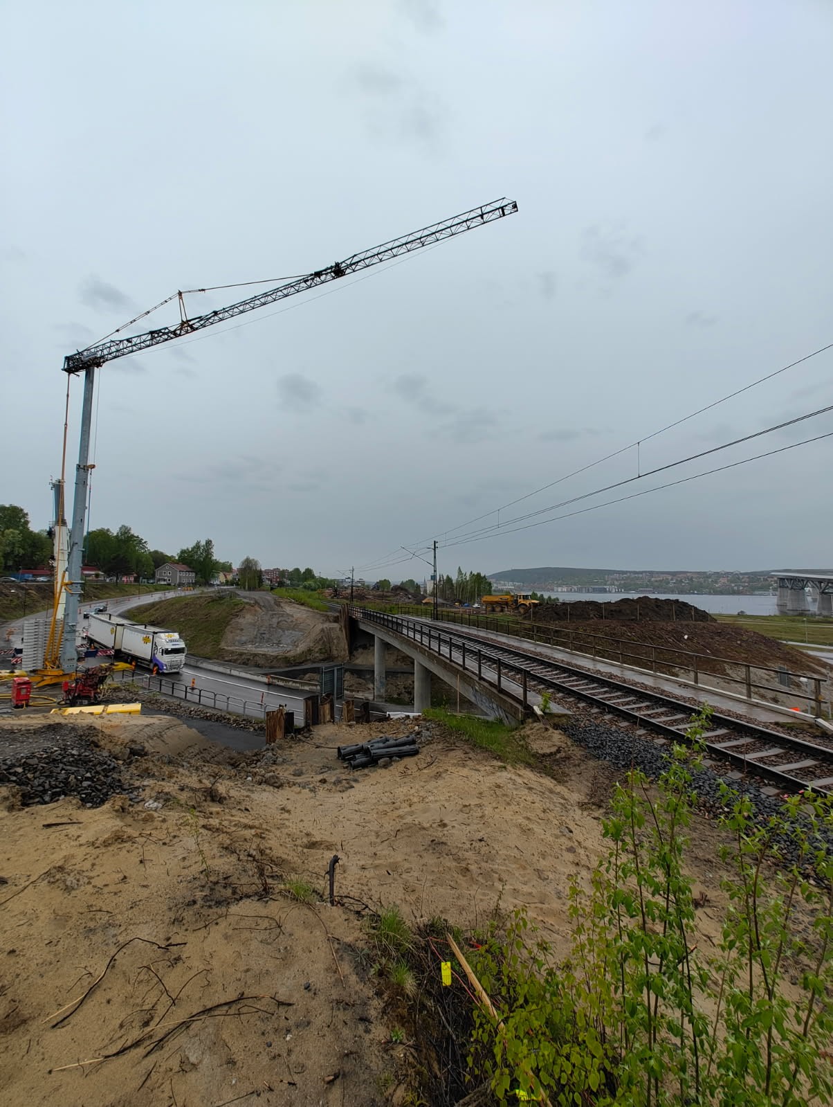 Spontarbeten vid Björneborgsgatan i samband med ett tågstopp 18 april 2026. Vid järnvägsbron över Björneborgsgatan står en hög byggkran. Kranen lyfter stålspont upp mot järnvägen där varselklädda arbetare står samt en grävmaskin.