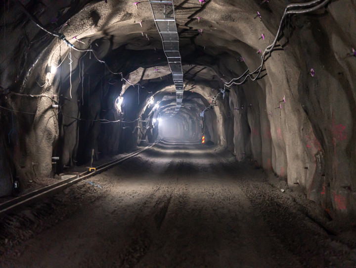 Inne i spårtunneln med bergväggar och det syns kabelränna och ledningar i taket
