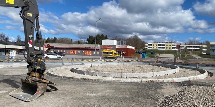 Centrumvägen i höjd med korsningen med Folketshusvägen. Kantsten utgör delar av en kommande cirkulationsplats. En grävmaskinarm med skopa intill pågående byggnation av cirkulationsplatsen. I bakgrunden ICA samt en tillfälligt uppställd matvagn.